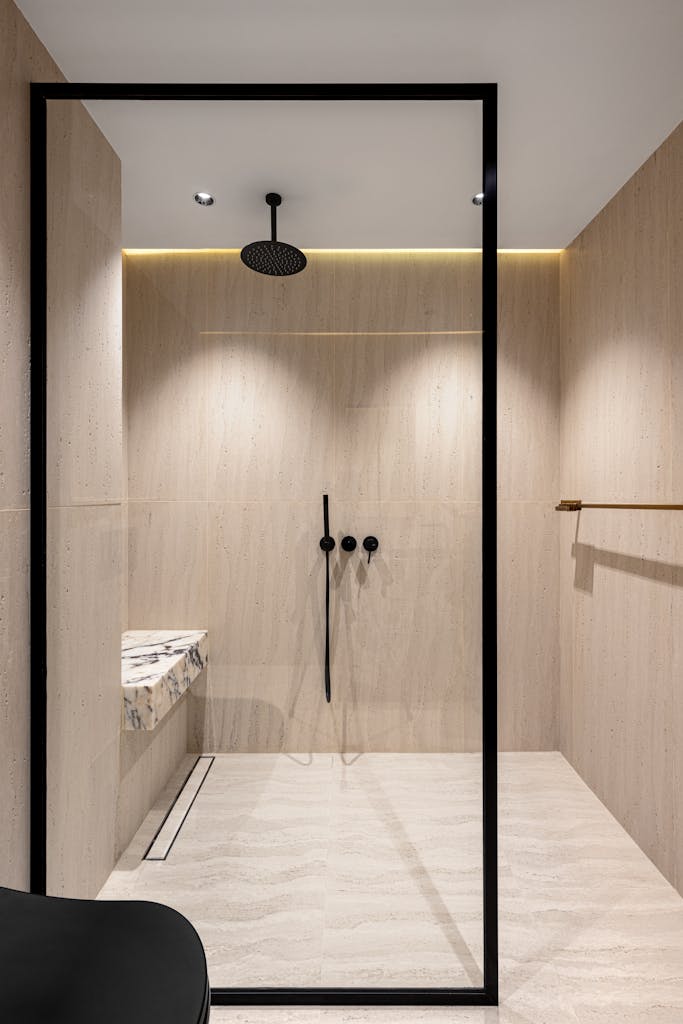 Sleek walk-in shower with light wood textures and modern fixtures.
